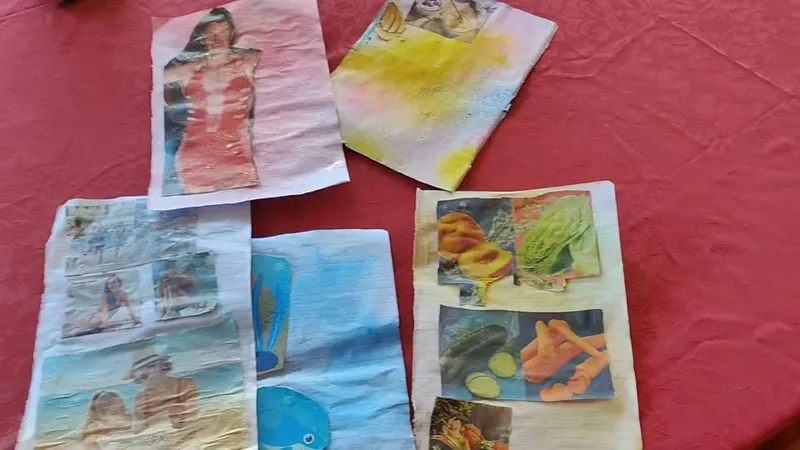 Fogli con collage di ritagli colorati, frutta e figure, realizzati dagli ospiti su una tovaglia rossa