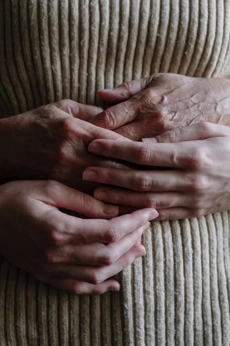 Due mani giovani stringono con dolcezza le mani di una persona anziana