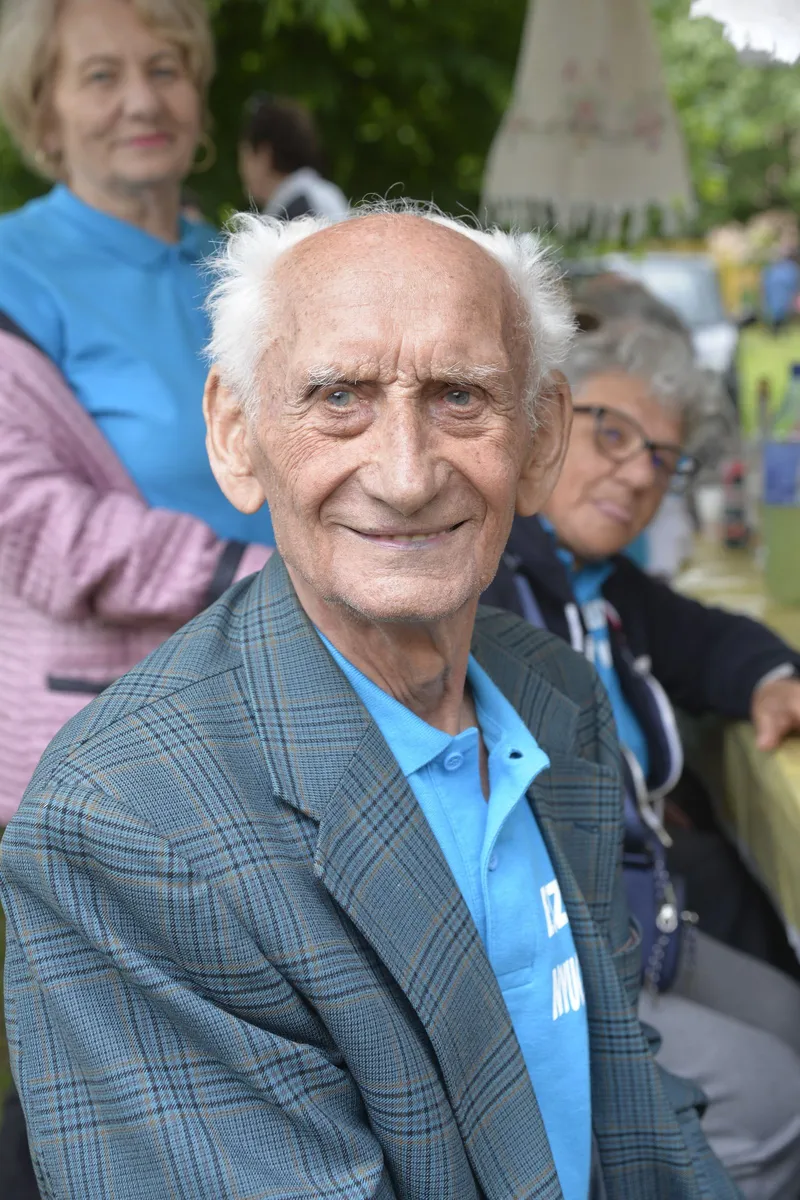 Un signore anziano sorride seduto tra altri ospiti